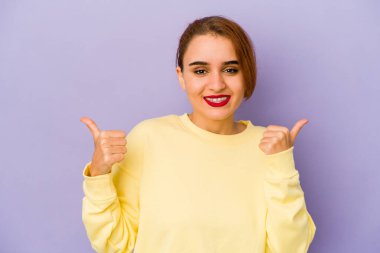 Genç Arap melez kadın iki parmağını da kaldırıyor, gülümsüyor ve kendinden emin..