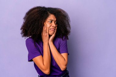 Genç Afro-Amerikalı kıvırcık kadın, mor arka planda izole edilmiş korkmuş ve korkmuş..