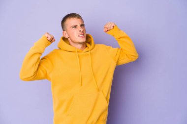 Genç, beyaz, yakışıklı bir adam zafer kazandıktan sonra yumruğunu kaldırıyor..