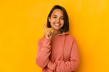 Sarıda izole edilmiş genç İspanyol kadın bir numarayı parmağıyla gösteriyor..