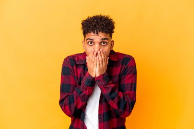 Genç Afro-Amerikalı kıvırcık adam mor renkte izole edilmiş ağzı elleriyle kapatıyor..