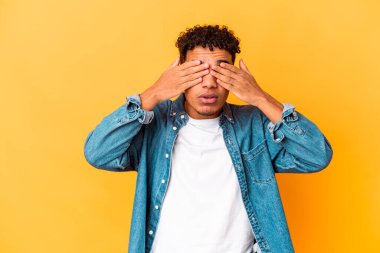 Genç Afro-Amerikalı kıvırcık adam, mor üzerine izole edilmiş, gözleri korkuyla kaplı, elleriyle..