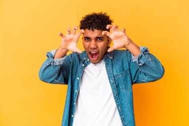 Genç Afro-Amerikan kıvırcık adamı, mor üzerine izole edilmiş, pençelerini kedi taklidi yaparken gösteriyor, agresif bir hareket..