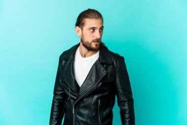 Uzun saçlı genç adam gülümseyen, neşeli ve hoş bakışlarını yana çevir..