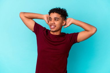 Genç Afro-Amerikalı kıvırcık adam mavi üzerine izole edilmiş kendinden emin, elleri başının arkasında.