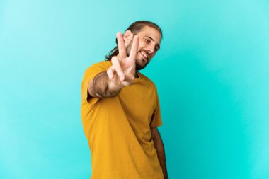 Uzun saçlı genç adam neşeli ve tasasız görünüyor. Barış sembolünü parmaklarıyla gösteriyor..