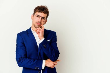 Beyaz arka planda izole edilmiş beyaz iş adamı şüpheli ve şüpheci bir ifadeyle yana bakıyor..
