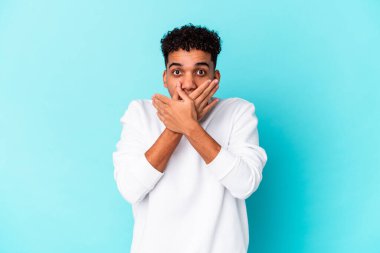 Genç Afro-Amerikan kıvırcık adamı, mavi renkte izole edilmiş, elleri ve ağzı kapalı..