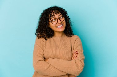 Genç Afrikalı Amerikalı Afro kadın kendini soyutlamış kollarını kavuşturarak gülümsüyor..