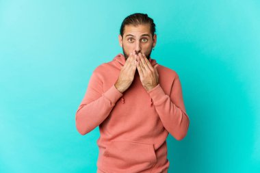 Uzun saçlı genç adam elleri ile ağzını kapatırken şok olmuş görünüyor..