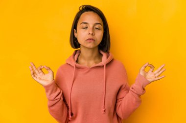 Genç İspanyol kadın, sıkı çalışma gününden sonra sarı gevşemeleri izole ederek yoga yapıyor..