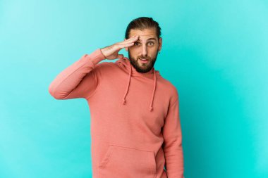 Uzun saçlı genç adam yüksek sesle bağırıyor, gözleri açık ve elleri gergin tutuyor..