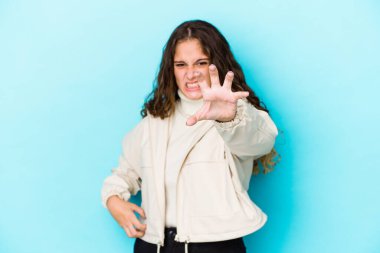 Kafkasyalı kıvırcık saçlı genç kadın pençelerini kedi taklidi yaparken gösteriyor, agresif bir hareket..