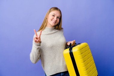 Genç Rus kadın seyahat etmek için bavul tutuyor zafer işareti gösteriyor ve gülümsüyor..