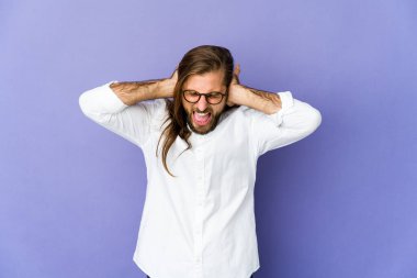 Uzun saçlı genç adam elleriyle kulaklarını kapatmış yüksek sesli sesler duymamaya çalışıyor..