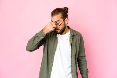 Uzun saçlı, başı ağrıyan, yüzüne dokunan bir genç..