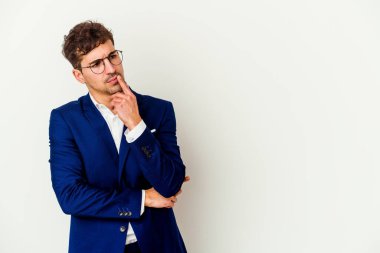 Beyaz arka planda izole edilmiş beyaz iş adamı şüpheli ve şüpheci bir ifadeyle yana bakıyor..