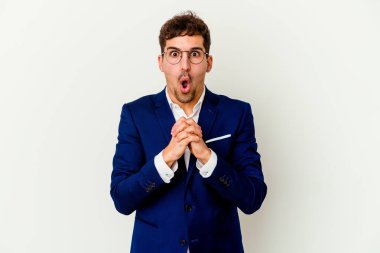 Beyaz arka planda yaşayan beyaz tenli genç bir adam şans için dua ediyor, şaşırıyor ve ağzını açıyor..