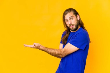 Uzun saçlı genç adam avucunun içinde bir kopya alanı tutuyor..