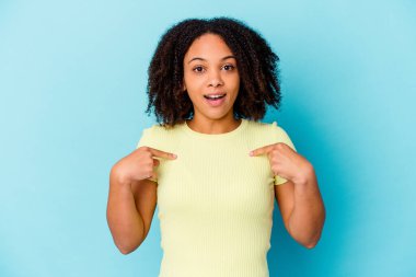 Genç Afro-Amerikan melez kadın kendini soyutlamış parmağını göstererek şaşırmış, geniş bir gülümsemeyle..