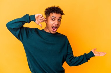 Mor üzerine izole edilmiş genç Afro-Amerikan kıvırcık adamı bir avuç içinde fotokopi alanı tutuyor, el üstünde tutuyor. Şaşırmış ve mutlu..