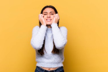 Sarı arka planda izole edilmiş genç bir Hintli kadın ağlıyor. Acı ve kafa karışıklığı gibi bir şeyden mutsuz..