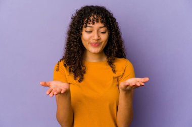 Genç Afrikalı Afro-Amerikan kadın elinde avuç içiyle kameraya bir şey sunuyor..