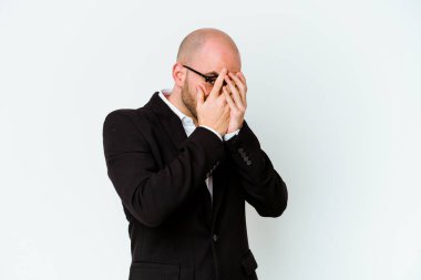 Genç, beyaz, kel bir adam mavi arka planda izole edilmiş. Korkmuş ve gergin parmaklarıyla göz kırp..