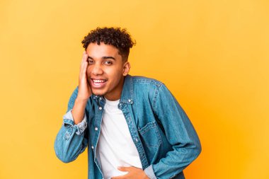 Genç Afro-Amerikalı kıvırcık adam Mor üzerine izole edilmiş mutlu bir şekilde gülüyor ve ellerini karnının üstünde tutarak eğleniyor..