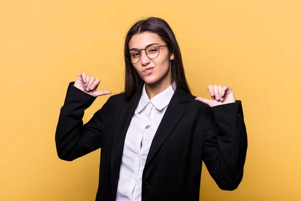 Young Indian business woman isolated on yellow background feels proud and self confident, example to follow.