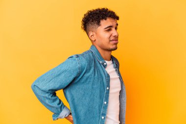 Genç Afro-Amerikalı kıvırcık adam Mor renkte izole edilmiş sırt ağrısı çekiyor.