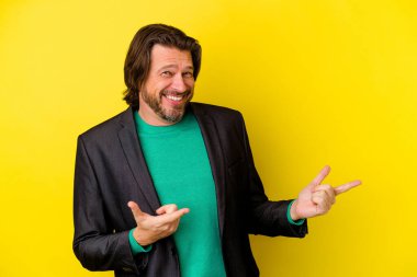 Orta yaşlı beyaz bir adam sarı arka planda izole edilmiş neşeli bir şekilde gülüyor. Mutluluk kavramı.