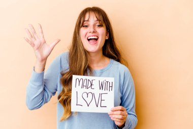 Genç, beyaz bir kadın, elinde aşk levhasıyla yalnız başına güzel bir sürpriz bekliyor, heyecanlı ve el kaldırıyor..