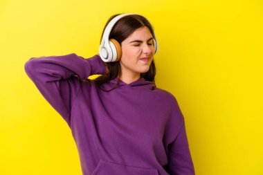 Pembe arka planda izole edilmiş kulaklıklı müzik dinleyen beyaz bir kadın sabit yaşam tarzından dolayı boyun ağrısı çekiyor..