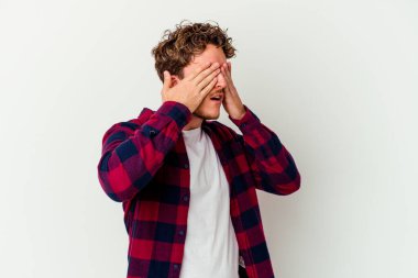 Beyaz arka planda izole edilmiş genç beyaz bir adam elleriyle gözlerini kapatmaktan korkuyor..