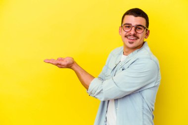 Sarı arka planda izole edilmiş beyaz bir adam palmiyesinde bir kopya alanı tutuyor..