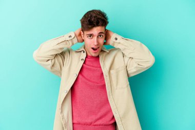 Renkli arka planda poz veren beyaz bir genç. 