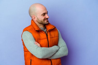 Kafkasyalı kel adam mor arka planda izole edilmiş gülüyor ve eğleniyor..