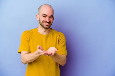 Kafkasyalı kel adam mor arka planda izole edilmiş dudaklar kıvrılıyor ve hava öpücüğü vermek için avuç içleri tutuyor..