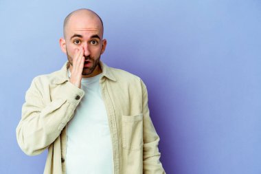 Mor arka planda izole genç beyaz kel adam gizli bir sıcak fren haberi söylüyor ve yana bakıyor