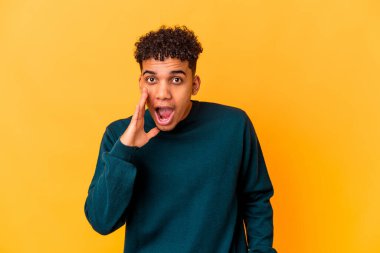 Genç Afro-Amerikalı kıvırcık adam mor renkte izole edilmiş yüksek sesle bağırıyor, gözlerini açık ve ellerini gergin tutuyor.