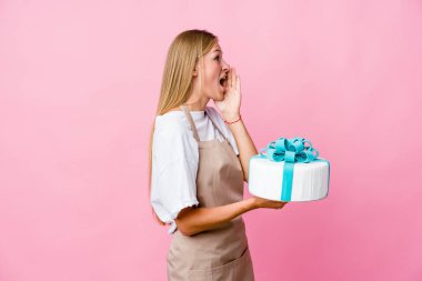 Genç Rus fırıncı kadın elinde lezzetli bir pasta tutarak bağırıyor ve avuç içini açık tutuyor..