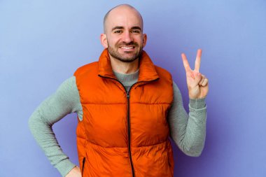 Mor arka planda izole genç beyaz kel adam iki numaranın parmakları olduğunu gösteriyor..