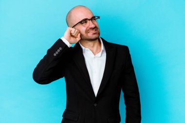 Genç beyaz, kel bir adam mavi arka planda izole edilmiş zafer, tutku ve coşkuyu kutluyor, mutlu bir ifade..