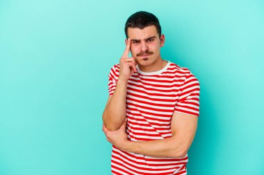 Mavi arka planda izole edilmiş genç beyaz adamın yanakları şişer, yorgun bir ifadesi vardır. Yüz ifadesi kavramı.