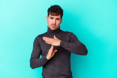 Mavi arka planda izole edilmiş genç beyaz bir adam bir mola hareketi gösteriyor..