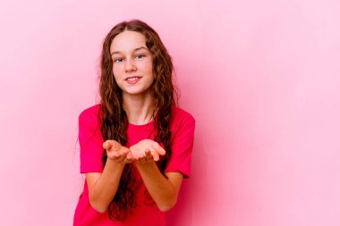 Küçük beyaz kız pembe arka planda izole edilmiş dudaklar kıvrılmış ve hava öpücüğü göndermek için avuç içleri tutulmuş..