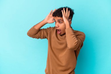 Genç Afro-Amerikalı kıvırcık adam mavi renkte izole edilmiş, çok heyecanlı, tutkulu, bir şeyden memnun..