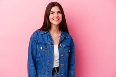 Pembe arka planda izole edilmiş beyaz bir kadın. Kendine güveni tam. Kalçalarını tutuyor..