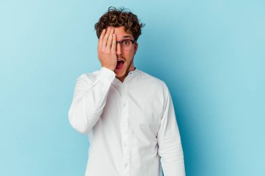 Kafkasyalı genç iş adamı mavi arka planda izole edilmiş, yüzünün yarısını palmiye ile kaplayarak eğleniyor..